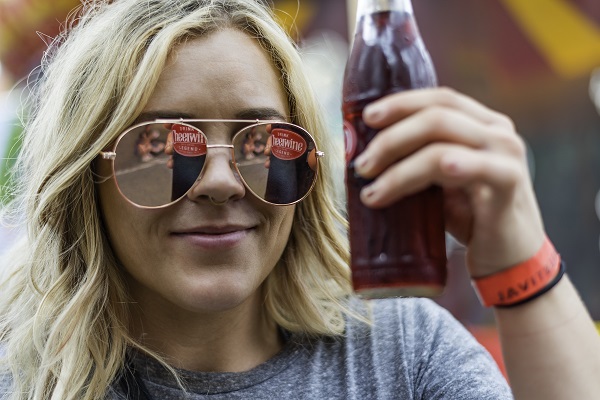 Girl posing with Cheerwine bottle reflected in her sunglasses